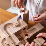 Child placing marbles in the Cuboro Standard wooden marble run  32 piece set, set up on a table.