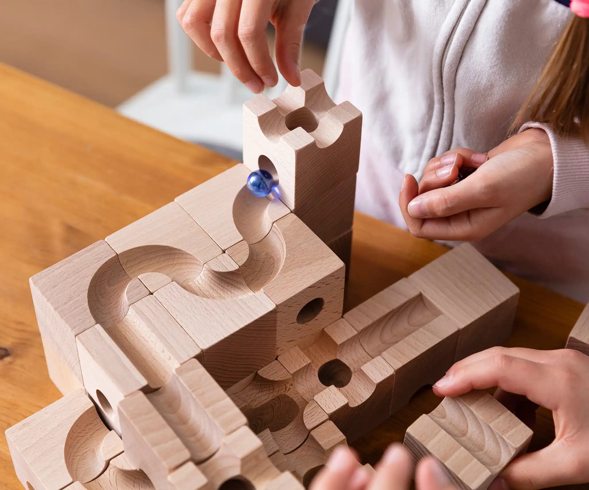 Child placing marbles in the Cuboro Standard wooden marble run  32 piece set, set up on a table.
