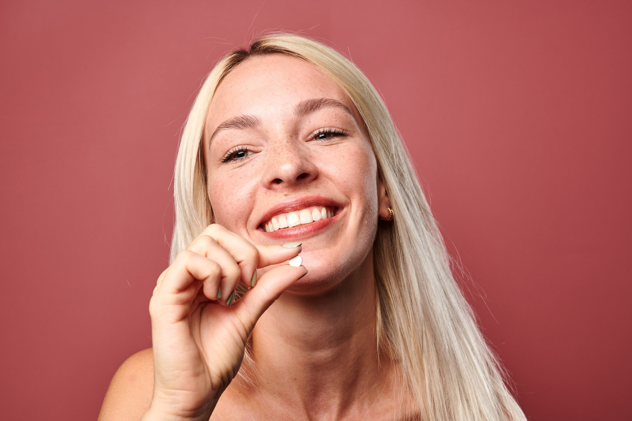 A woman holding a Denttabs toothpaste tablet