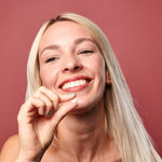A woman holding a Denttabs toothpaste tablet