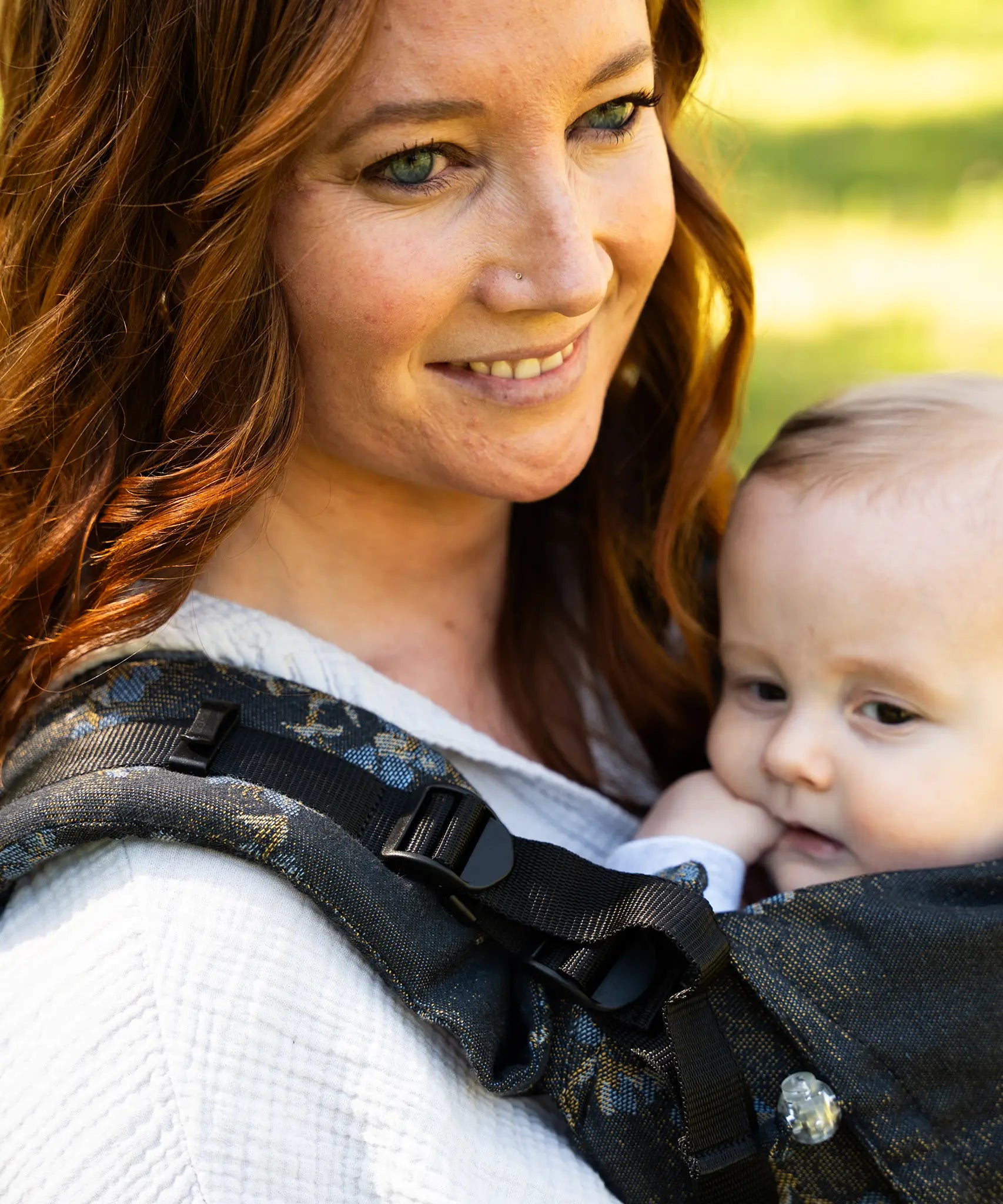 Mother wearing a Didymos didyfix baby carrier in blue blossom showing close up of padded adjustable shoulder strap 