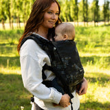 Mother wearing the Didymos didyfix carrier in blue blossom with a baby sitting inside. A soft structured full buckle carrier