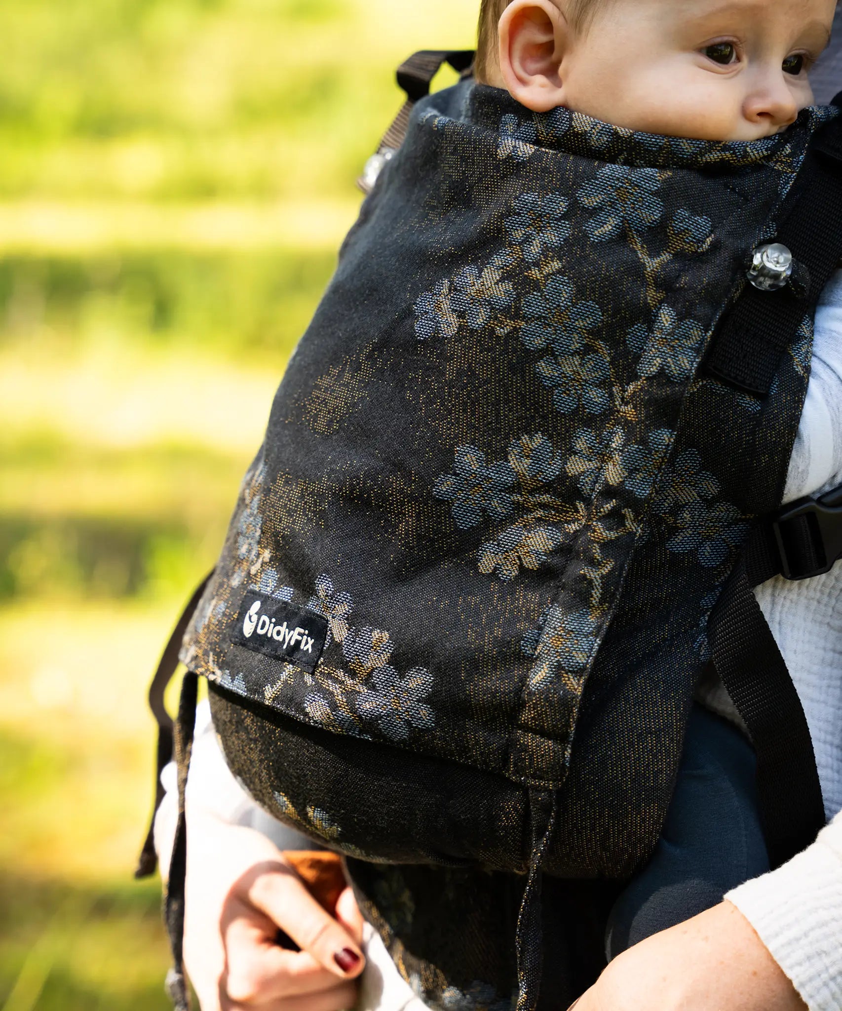Didymos didyfix carrier in blue blossom with a baby sitting inside showing close up of the design on cotton fabric
