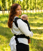Side of mother wearing the Didymos didyfix soft structured baby, full buckle carrier in blue blossom with a baby sitting inside 