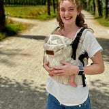 Mother wearing a Didymos didyfix full buckle baby carrier in Trias cream linen in the frontal position showing adjustable neck/head rest 