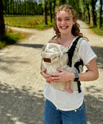 Mother wearing a Didymos didyfix full buckle baby carrier in Trias cream linen in the frontal position showing adjustable neck/head rest 