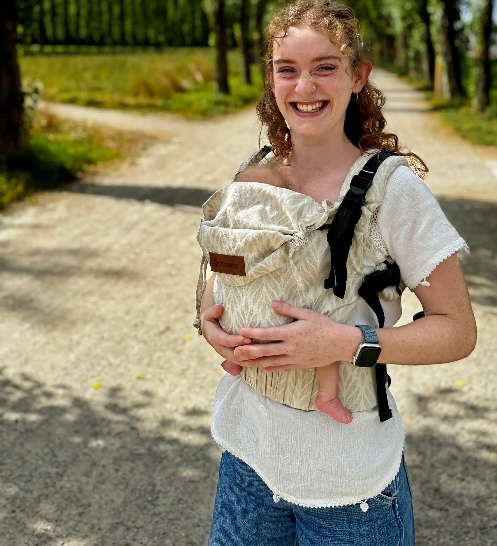 Mother wearing a Didymos didyfix full buckle baby carrier in Trias cream linen in the frontal position showing adjustable neck/head rest 