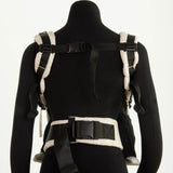 Back of a Didymos didyfix baby carrier in cream shown on mannequin. showing padded shoulder straps and buckle fasteners