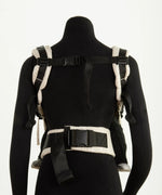 Back of a Didymos didyfix baby carrier in cream shown on mannequin. showing padded shoulder straps and buckle fasteners