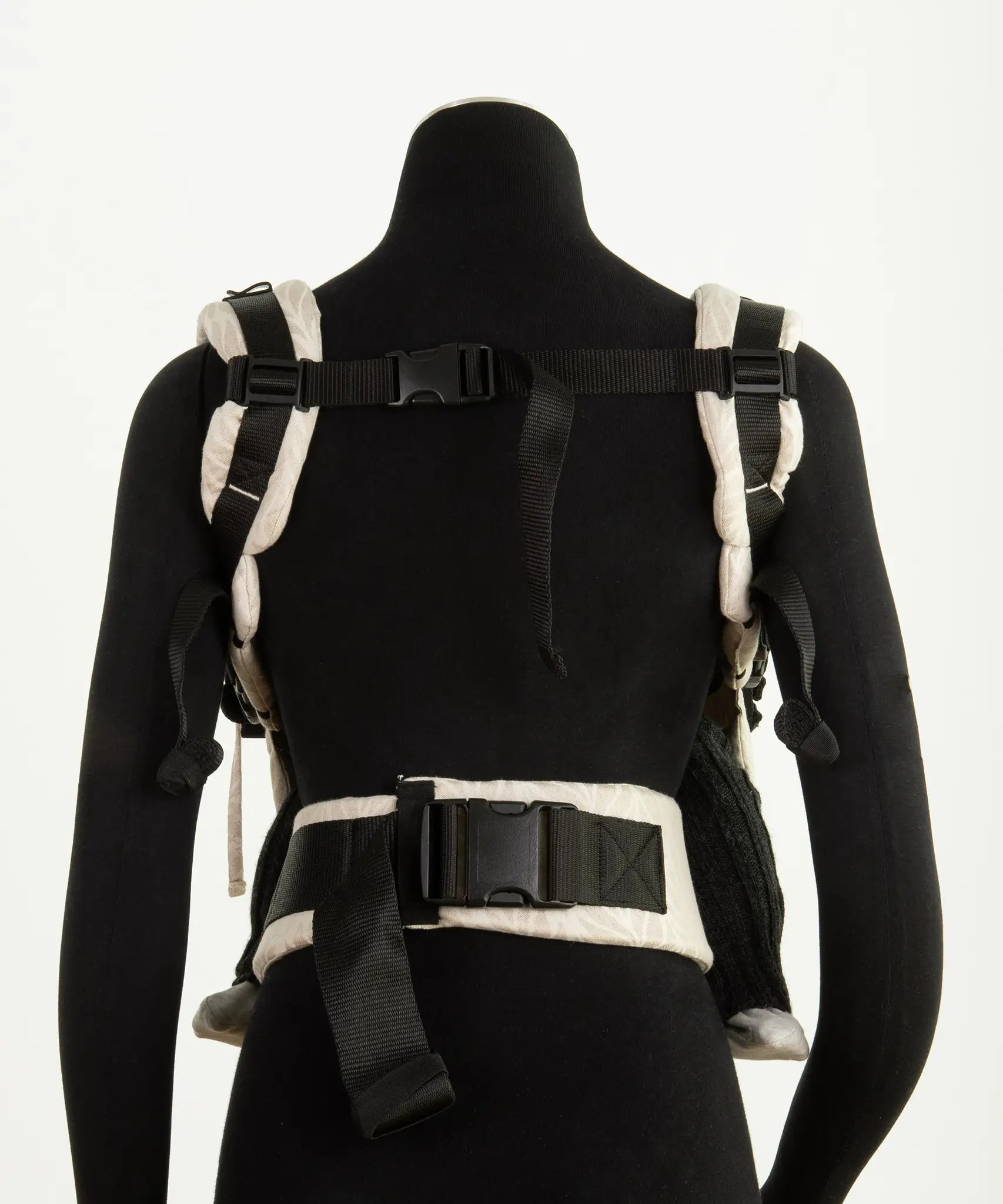 Back of a Didymos didyfix baby carrier in cream shown on mannequin. showing padded shoulder straps and buckle fasteners