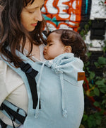 Side of mother carrying a baby in the Didymos didyfix soft structured baby carrier in ocean showing neck/head rest detail
