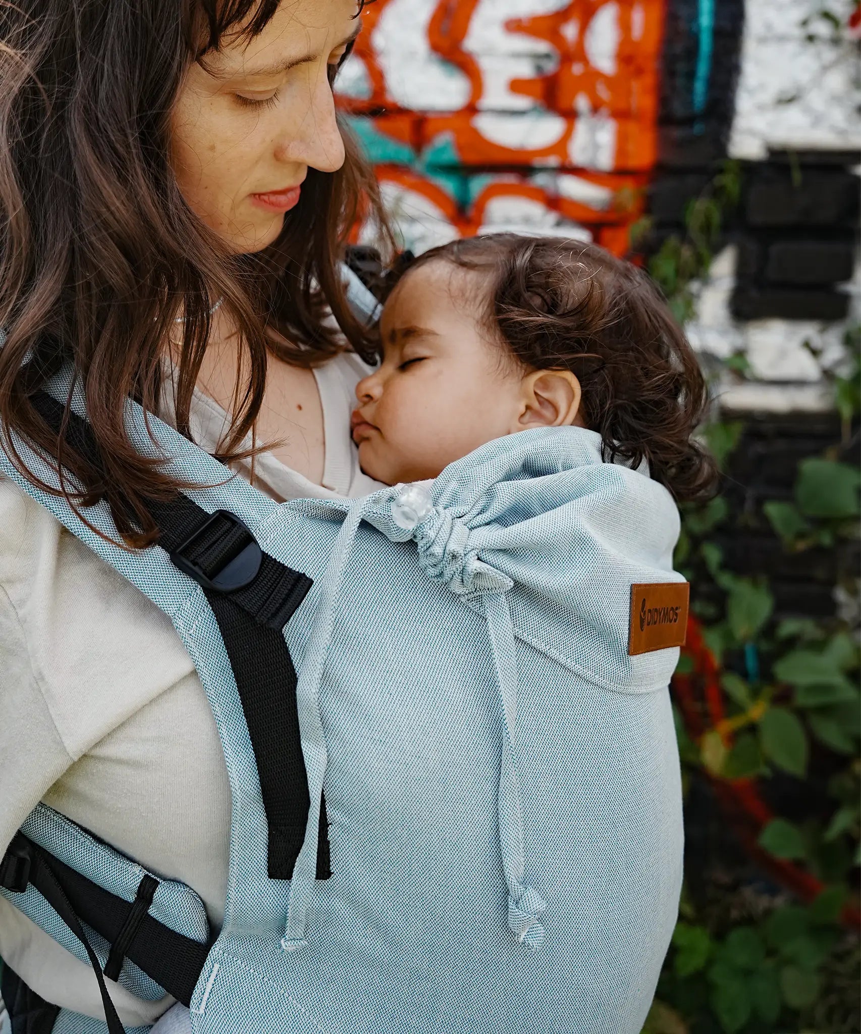 Side of mother carrying a baby in the Didymos didyfix soft structured baby carrier in ocean showing neck/head rest detail