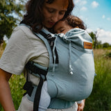 Mother  carrying a baby in a Didymos didyfix full buckle baby carrier in ocean in the frontal position