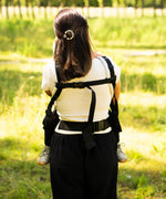 Back of mother wearing a didymos didyfix full buckle baby carrier in the frontal position showing padded shoulders and fastened buckles