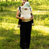 Mother carrying a baby in the frontal position in a Didymos didyfix full buckle soft structured baby carrier in sand colour