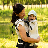 Side of mother carrying a baby in the frontal position in a Didymos didyfix full buckle baby carrier in sand colour showing neck rest supporting baby's head