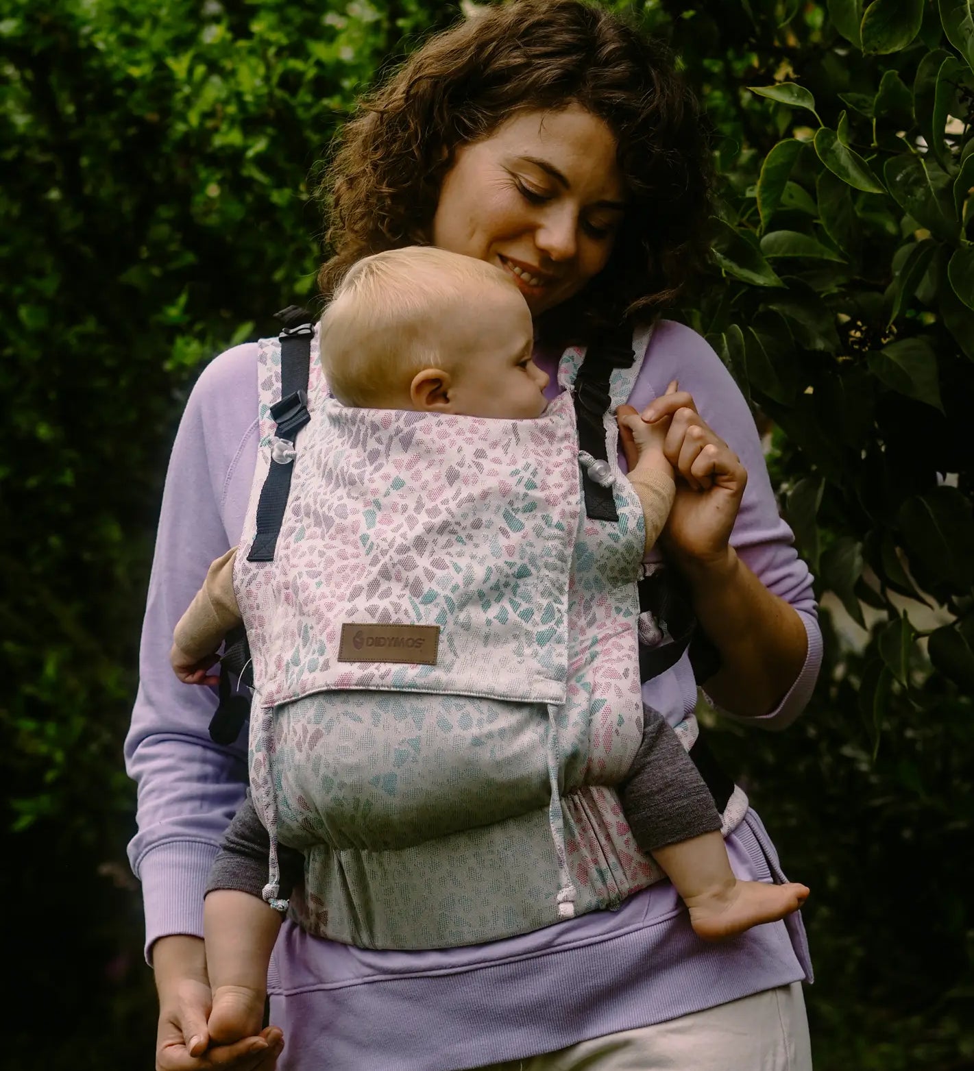Mother carrying a baby in the frontal position in the Didymos didyfix soft structured full buckle carrier in summer mosaic