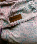 Summer mosaic design on the Didymos didyfix baby carrier showing a pink background with repeating pastel mosaic shapes and a brand patch on cotton fabric