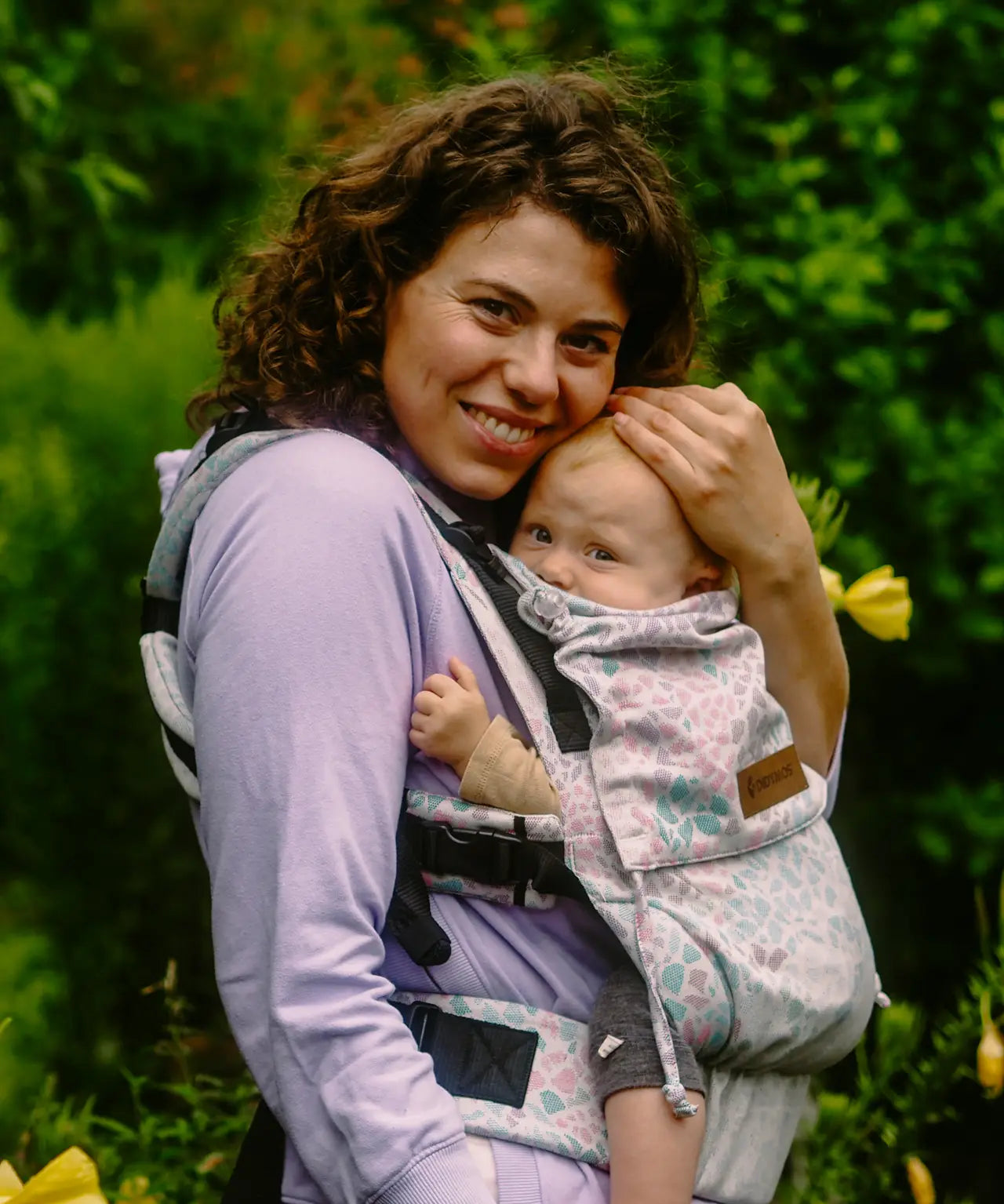 Side of mother carrying baby in the Summer mosaic Didymos didyfix soft structured cotton carrier in the frontal position 