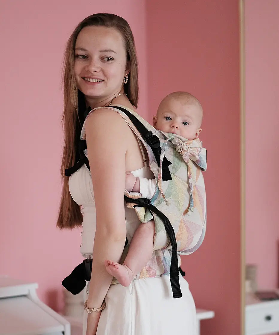 Side of mother carrying a baby in the Zephyr Didymos didyfix full buckle soft structured cotton carrier in the back position 