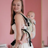 Side of mother carrying a baby in the Zephyr Didymos didyfix full buckle soft structured cotton carrier in the back position 