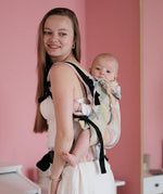 Side of mother carrying a baby in the Zephyr Didymos didyfix full buckle soft structured cotton carrier in the back position 