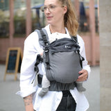 Mother carrying a baby in a Didymos didyfix full buckle baby carrier double anthracite in the frontal position. 