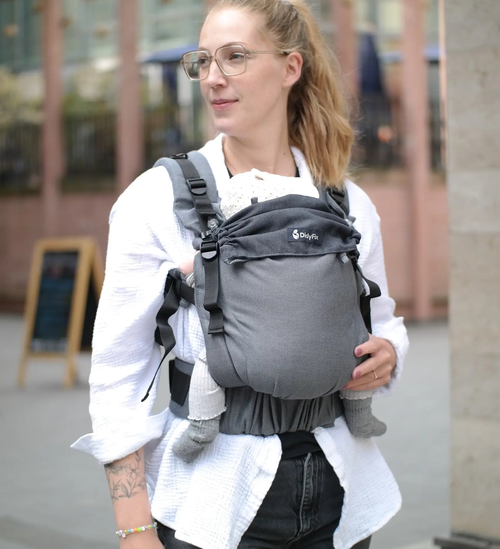Mother carrying a baby in a Didymos didyfix full buckle baby carrier double anthracite in the frontal position. 