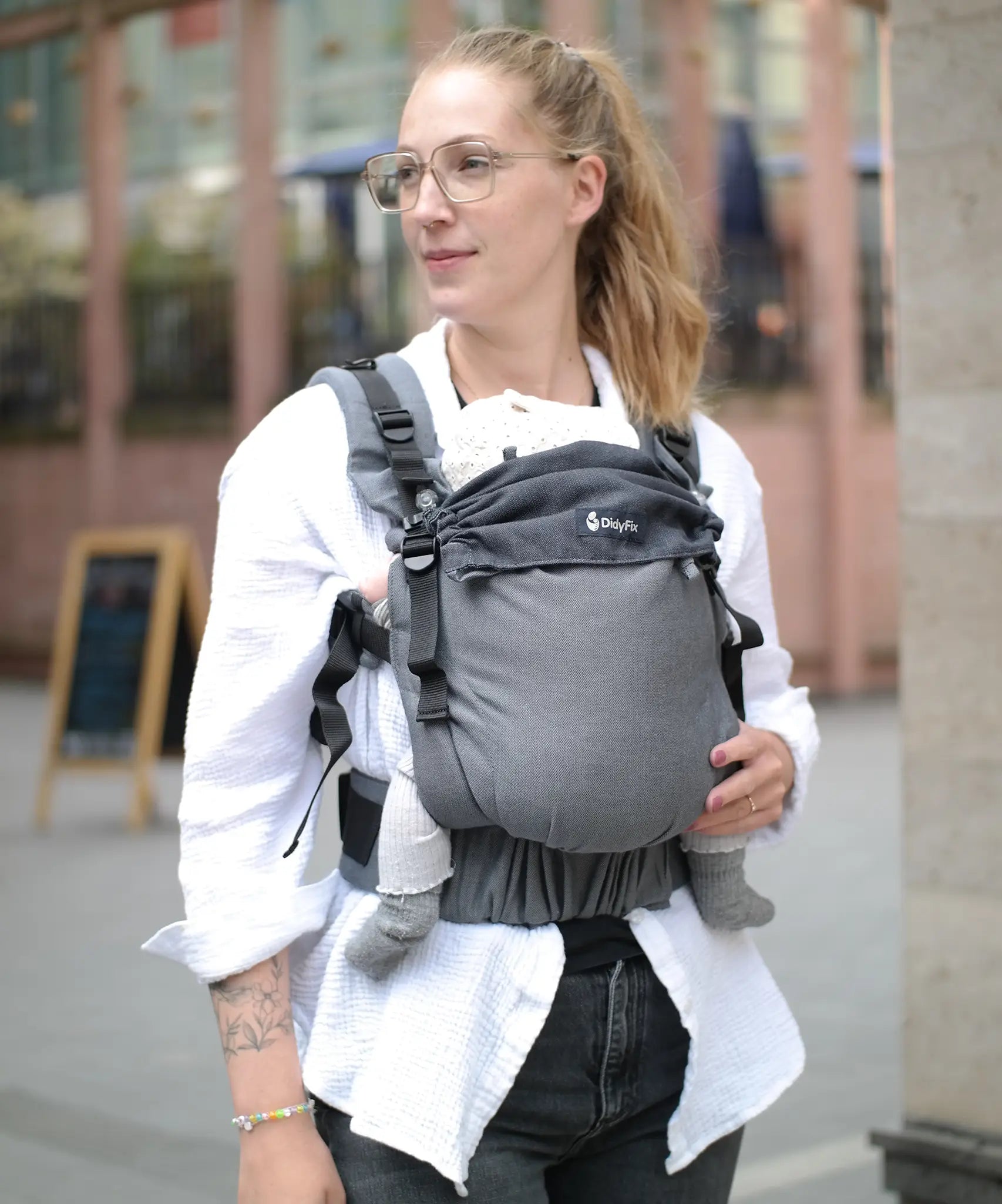 Mother carrying a baby in a Didymos didyfix full buckle baby carrier double anthracite in the frontal position. 