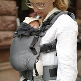 Side of mother wearing a Didymos didyfix baby full buckle carrier in double anthracite with a baby sitting inside