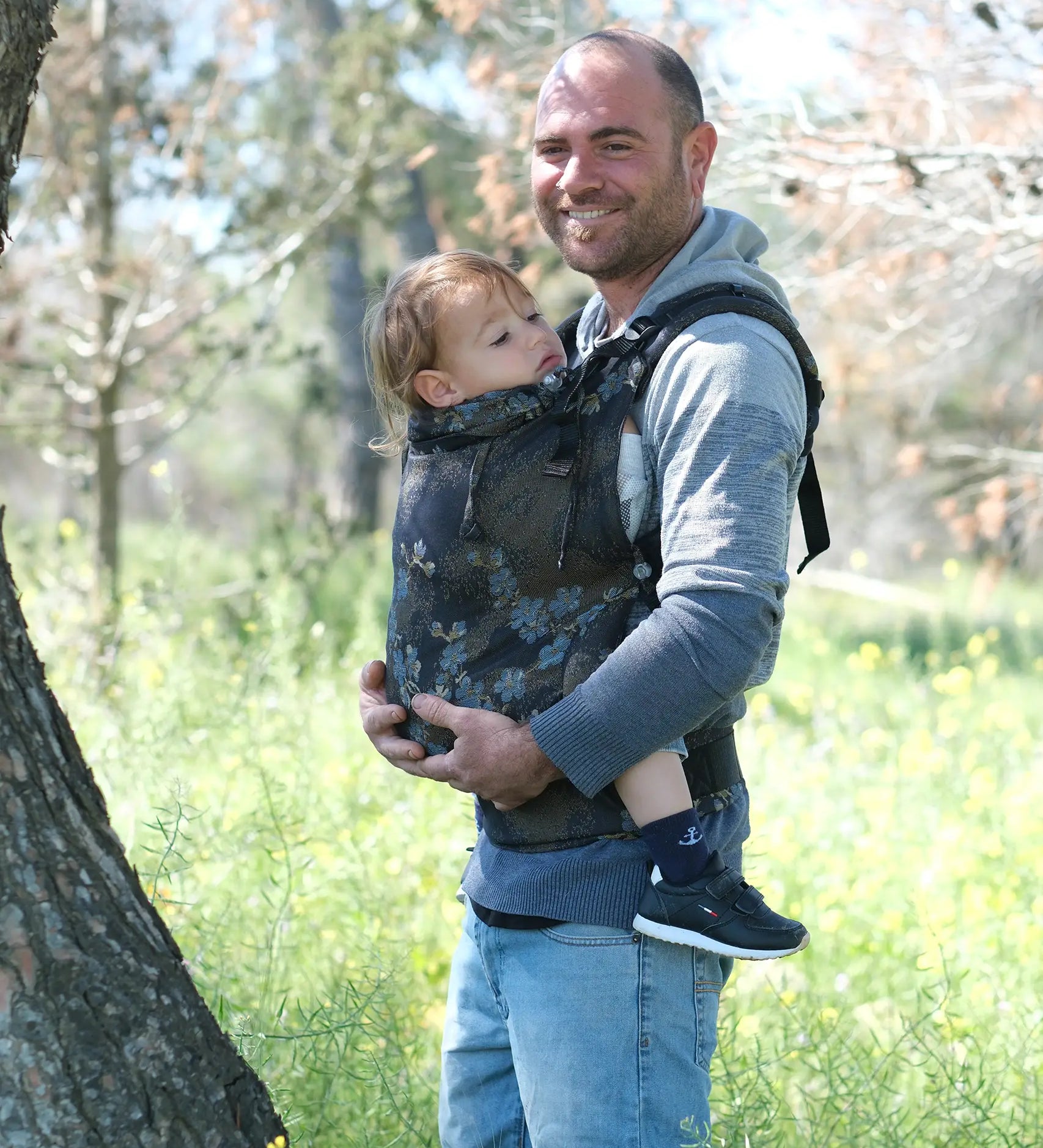 Father carrying a toddler in the blue blossom Didymos didyfix full buckle toddler carrier in the frontal position.  