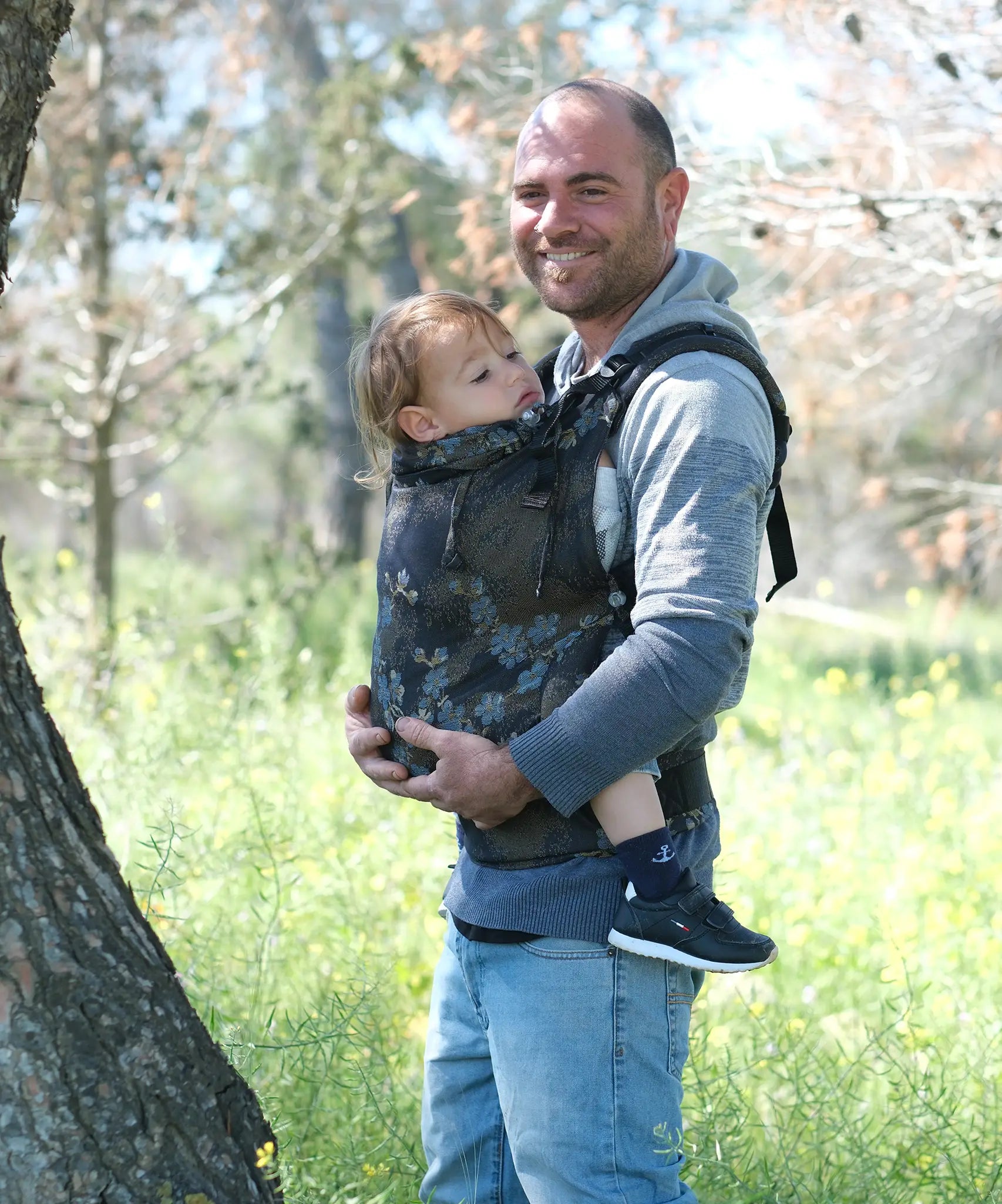 Father carrying a toddler in the blue blossom Didymos didyfix full buckle toddler carrier in the frontal position.  