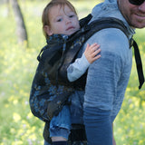 Father carrying a toddler in the blue blossom Didymos didyfix full buckle toddler carrier in the back position.  