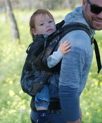 Father carrying a toddler in the blue blossom Didymos didyfix full buckle toddler carrier in the back position.  
