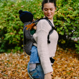 Side of mother carrying a small child on the back with a Didymos didyfix metro monochrom soft structured toddler carrier 