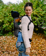 Side of mother carrying a small child on the back with a Didymos didyfix metro monochrom soft structured toddler carrier 