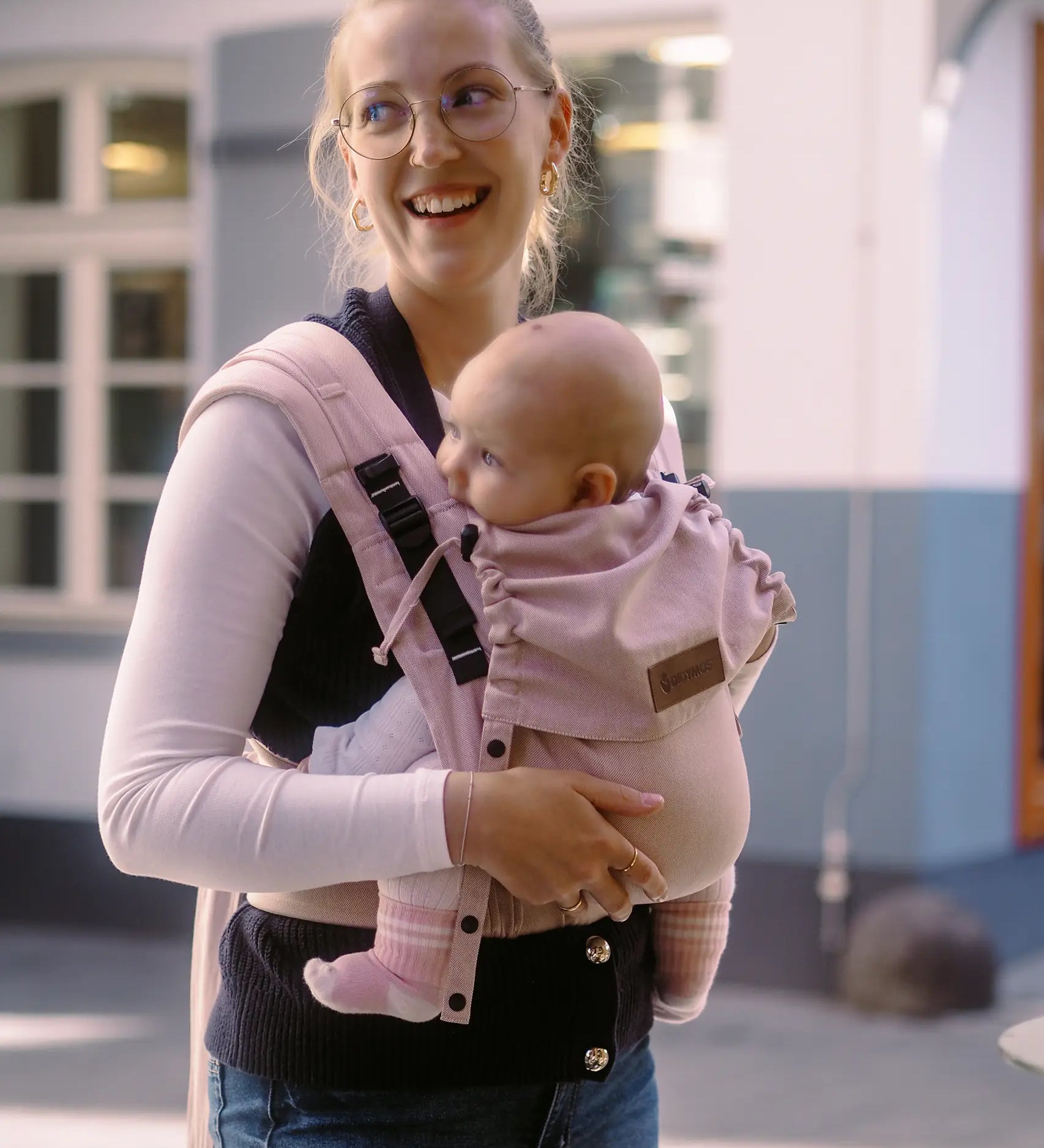 Mother carrying a baby in the cinammon Didymos didyflow half buckle carrier in the frontal postion 