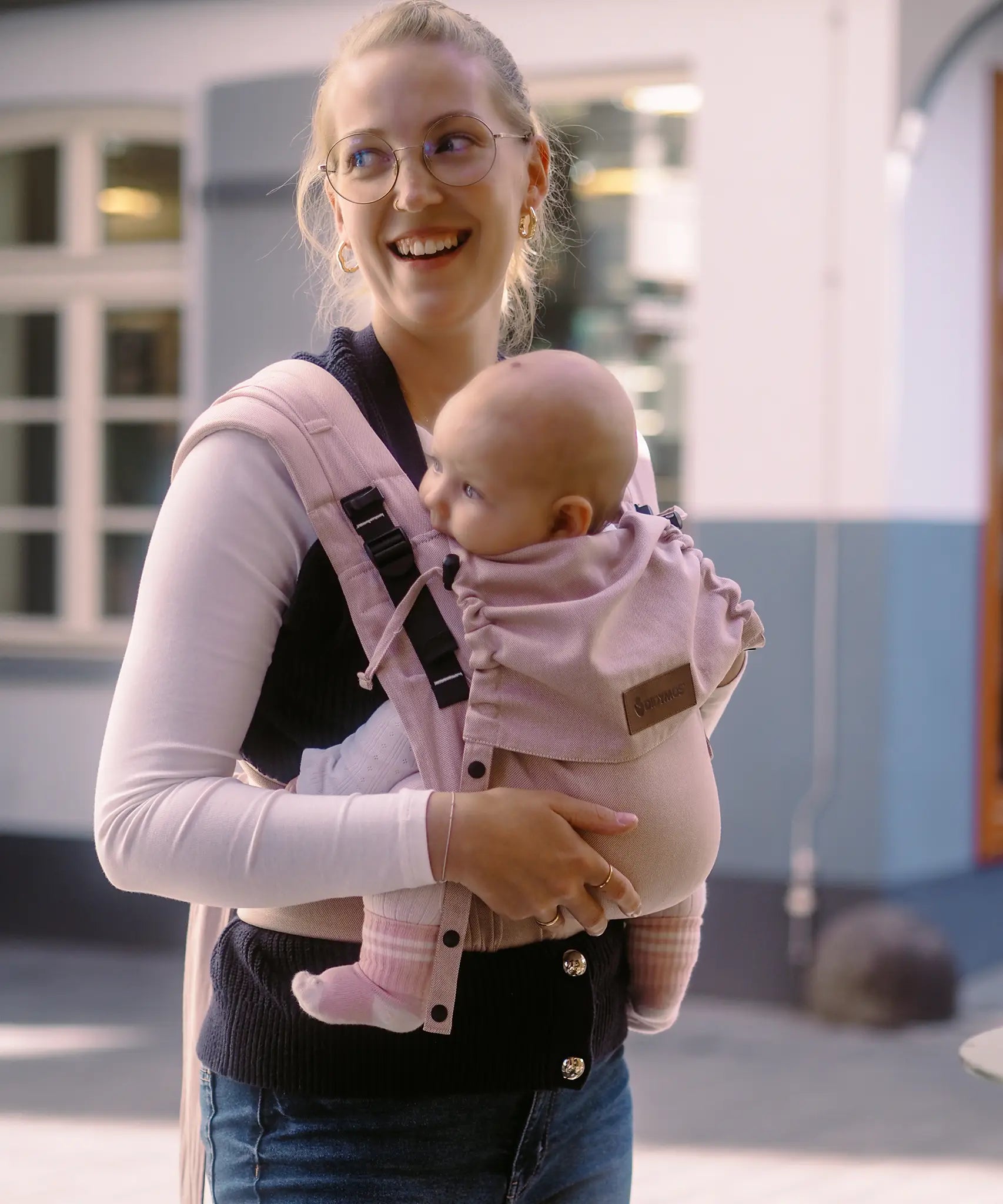 Mother carrying a baby in the cinammon Didymos didyflow half buckle carrier in the frontal postion 