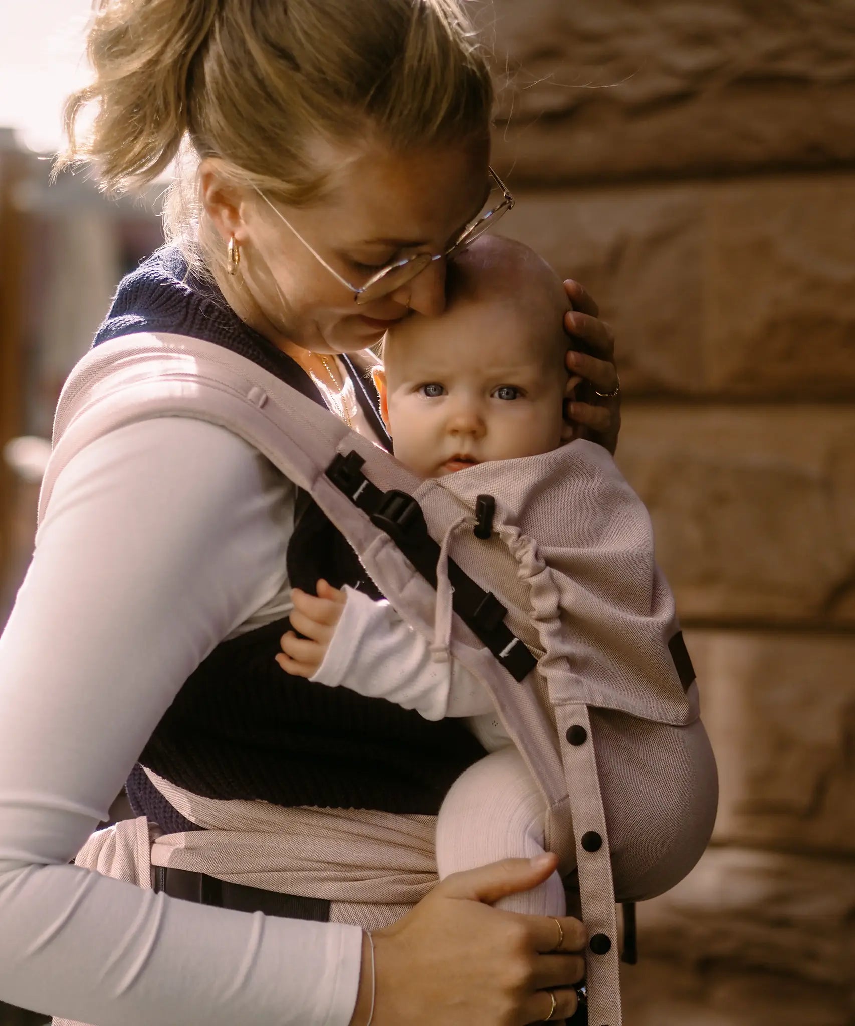 Side of Mother carrying a baby in a cinnamon Didymos didyflow half buckle cotton carrier in the frontal position 
