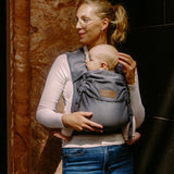 Mother carrying a baby in a Didymos didyflow half buckle half tie cotton carrier in the frontal position in double anthracite 