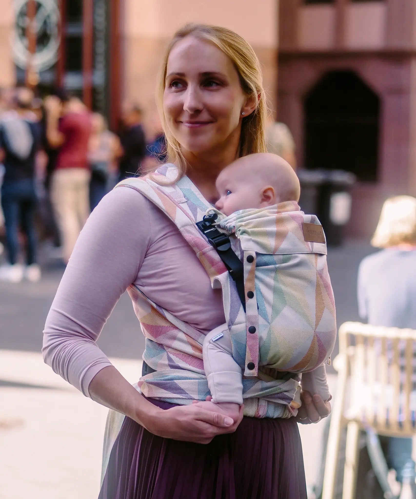 Mother carrying a baby in the zephyr  Didymos didyflow half buckle half tie cotton carrier in the frontal position