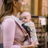 Side of mother carrying a baby in the zephyr Didymos didyflow half buckle half tie carrier in the frontal position showing neck/head rest detail