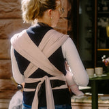 Back of mother wearing a Didymos didyflow cinnamon carrier showing half buckle half tie waist belt and double layered tie on shoulder straps