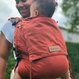Mother carrying a baby in the frontal position in the Didymos didyfix toddler carrier in rusty red