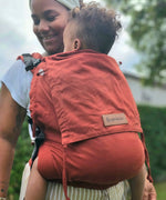 Mother carrying a baby in the frontal position in the Didymos didyfix toddler carrier in rusty red