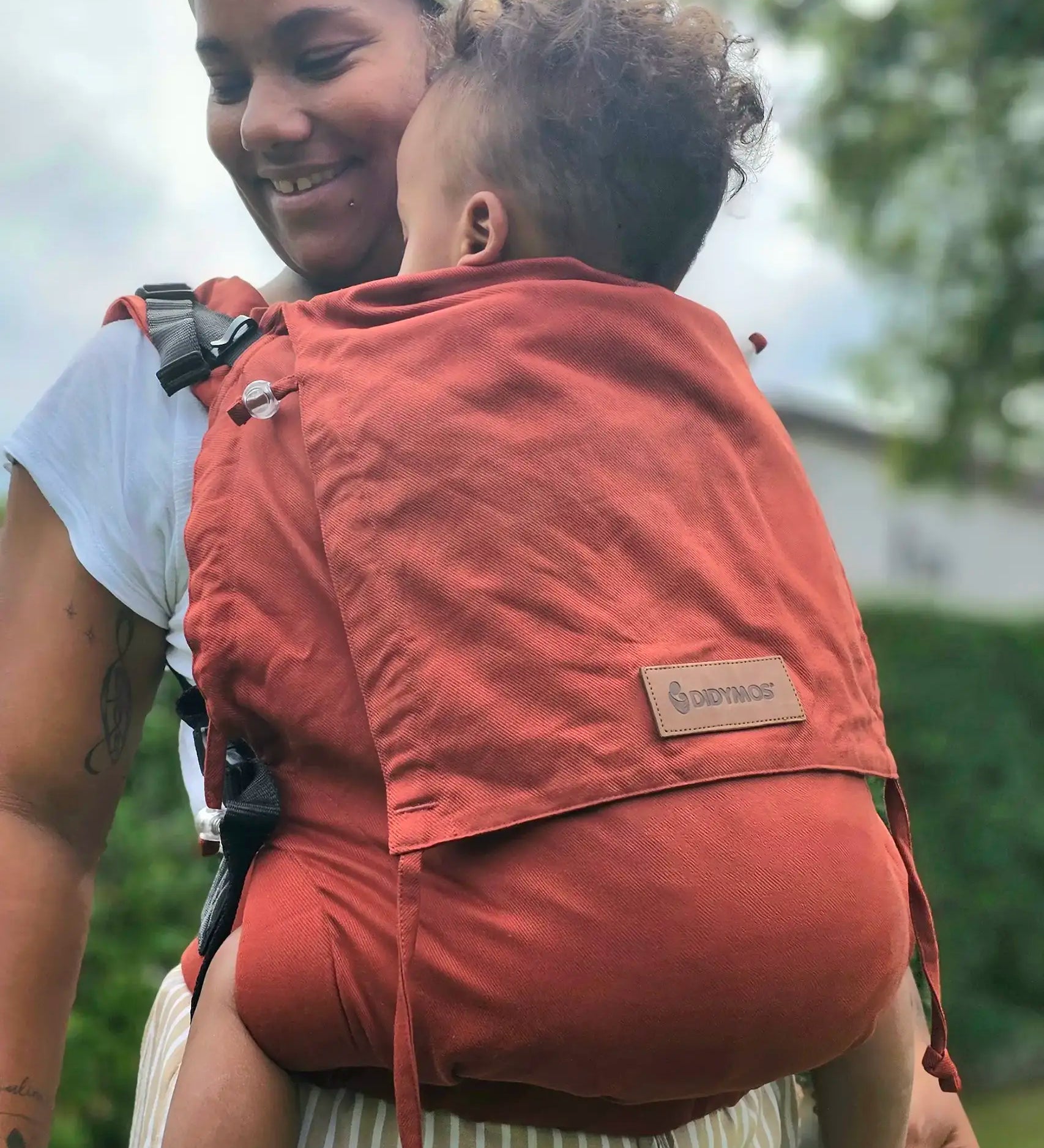 Mother carrying a baby in the frontal position in the Didymos didyfix toddler carrier in rusty red