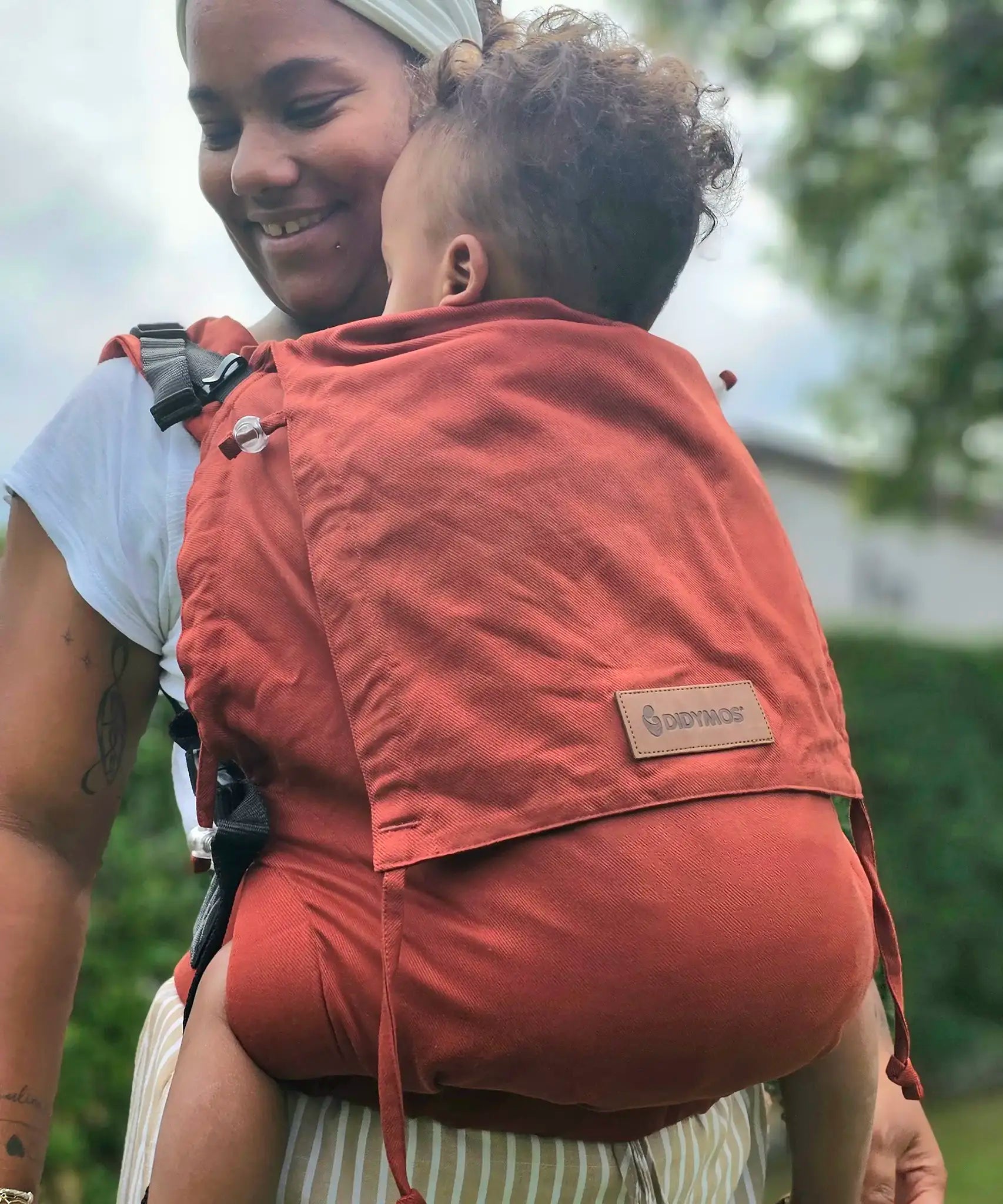 Mother carrying a baby in the frontal position in the Didymos didyfix toddler carrier in rusty red