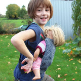 Side of child carrying a doll Didymos toy cotton carrier in the kipost design in the frontal position.