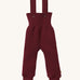 Disana organic merino wool dungarees in dark purple on a cream background.