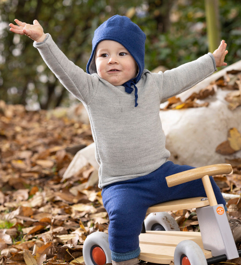 Disana organic merino wool melange jumper in a grey colour worn by a toddler playing on a toy bike